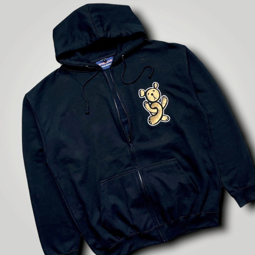 A black zip hoodie with a large , gold twisted teddy graphic embroidered on the left side, front